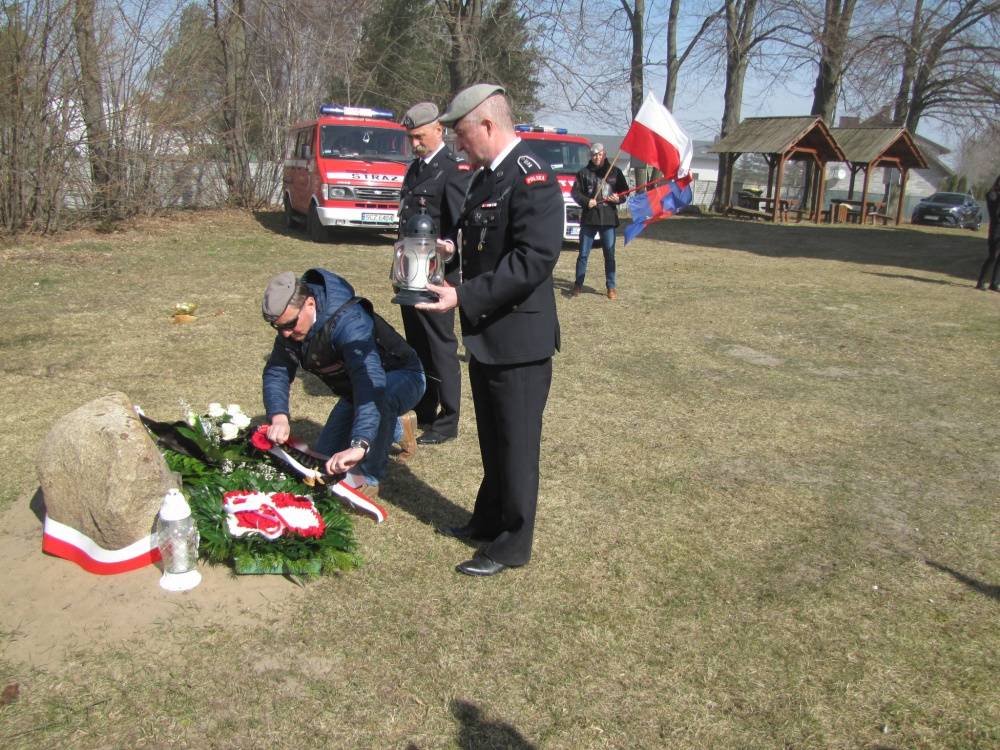 : Żołnierze jednostki specjalnej GROM składający kwiaty pod tablicą pamiątkową.